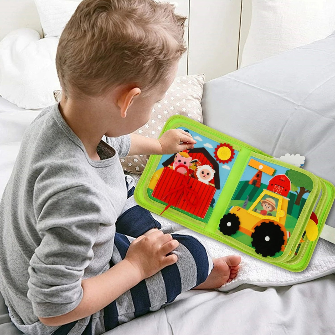 Dítě si hraje s interaktivní textilní knížkou Kinderspeech s motivem farmy pro rozvoj jemné motoriky a smyslového vnímání.