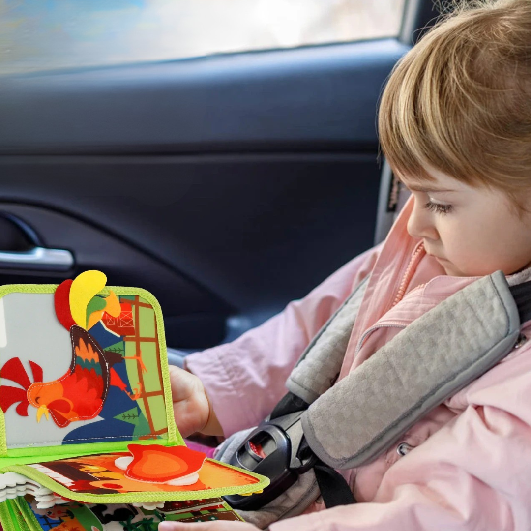 Malé dítě v autě si hraje s interaktivní textilní knížkou Kinderspeech pro rozvoj motoriky a smyslů během cestování.