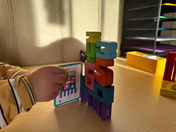 Dítě používá výukové karty a barevné dřevěné číslice Kinderspeech pro rozvoj logiky a učení čísel hrou.