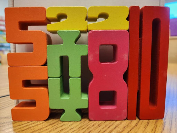 Detailní záběr na barevné dřevěné číslice Kinderspeech naskládané na sebe pro zábavnou výuku matematiky a rozvoj logiky.